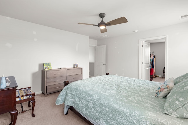 bedroom featuring visible vents, light carpet, a walk in closet, baseboards, and ceiling fan