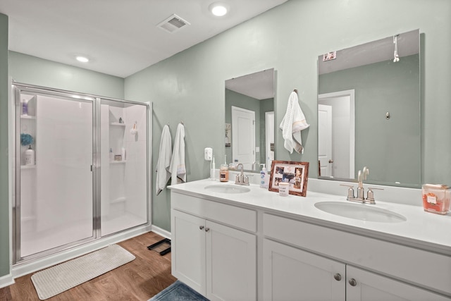 full bathroom with a sink, visible vents, wood finished floors, and a shower stall