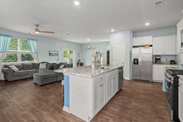 kitchen with visible vents, a ceiling fan, a sink, open floor plan, and stainless steel appliances