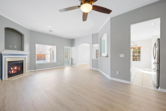 unfurnished living room with a premium fireplace, light wood-type flooring, ceiling fan, and ornamental molding