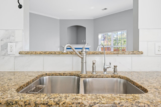 kitchen with sink, ornamental molding, and light stone countertops