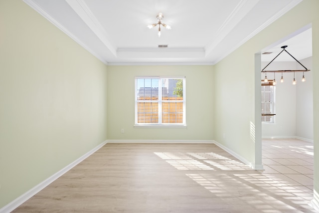 spare room featuring a tray ceiling, ornamental molding, and a chandelier