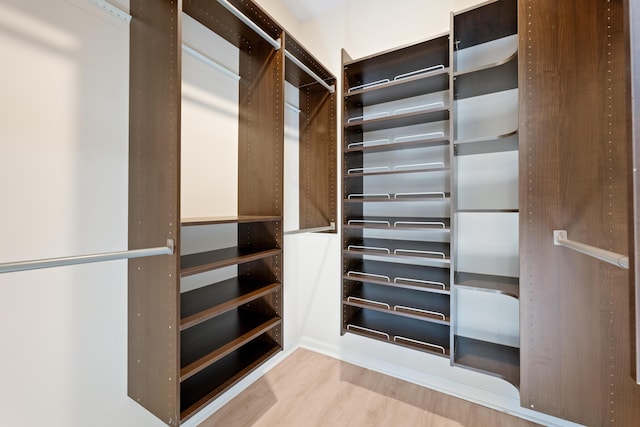 walk in closet with light hardwood / wood-style flooring