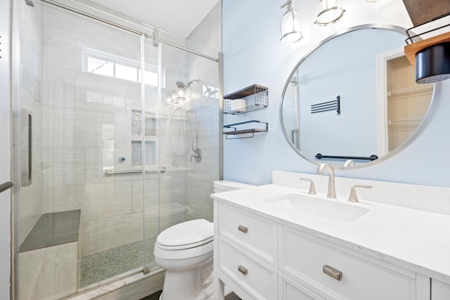 bathroom featuring a shower with door, toilet, and vanity