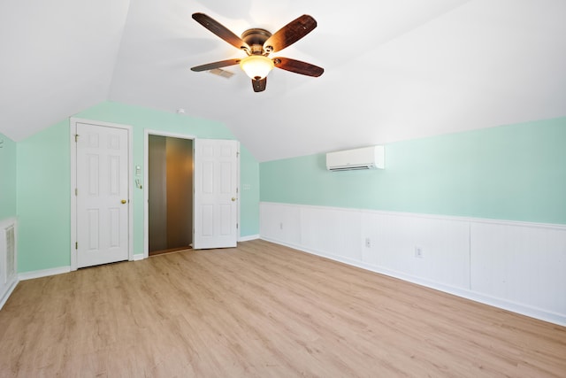 additional living space featuring ceiling fan, light wood-type flooring, a wall unit AC, and lofted ceiling