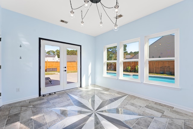 unfurnished room with a chandelier and french doors