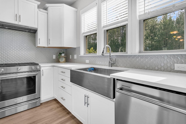 kitchen featuring sink, decorative backsplash, light wood-type flooring, white cabinetry, and stainless steel appliances