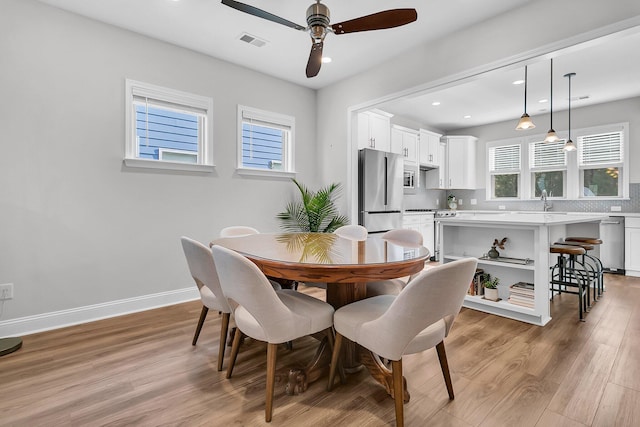 dining space with ceiling fan, light hardwood / wood-style flooring, and sink