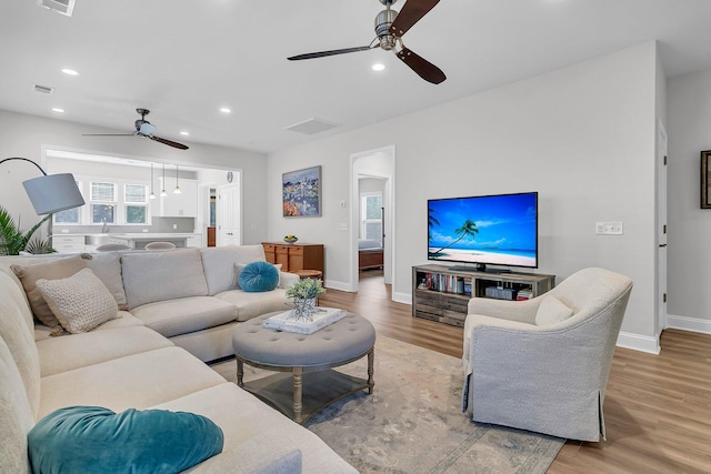 living room with ceiling fan, light wood-type flooring, and sink