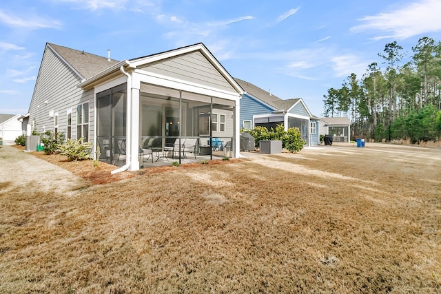 back of property featuring a lawn, a patio area, a sunroom, and central AC unit