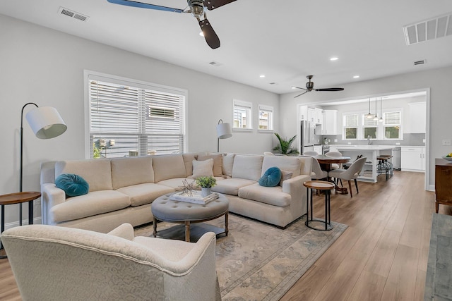 living room with ceiling fan and light hardwood / wood-style flooring