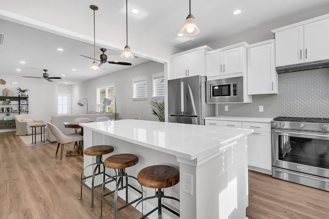 kitchen featuring white cabinetry, ceiling fan, decorative light fixtures, a kitchen island, and appliances with stainless steel finishes