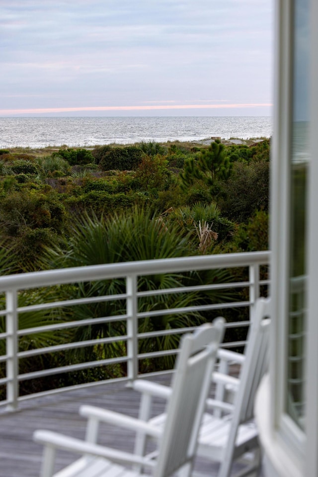 balcony at dusk with a water view and a beach view