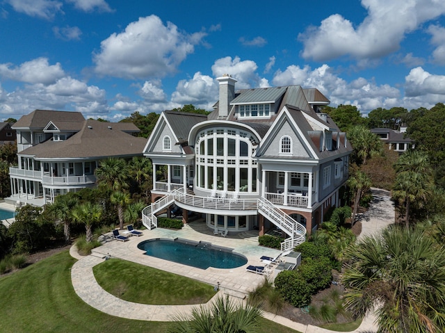 back of property with a patio, a pool with hot tub, and a sunroom