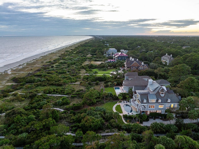 aerial view at dusk featuring a water view and a beach view