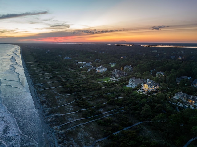 aerial view at dusk featuring a water view and a view of the beach