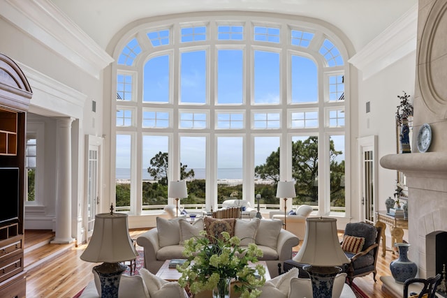 sunroom / solarium with a high end fireplace and a water view