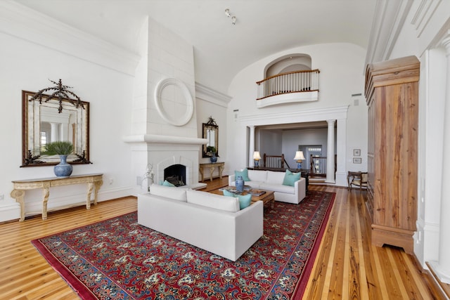 living room featuring ornamental molding, hardwood / wood-style floors, and a large fireplace