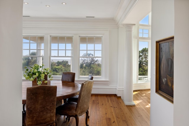 dining room featuring ornamental molding, ornate columns, and light wood-type flooring