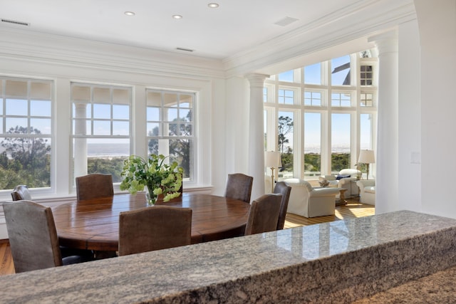 dining area featuring decorative columns, ornamental molding, and hardwood / wood-style floors