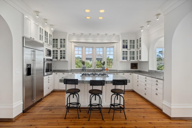 kitchen featuring light hardwood / wood-style flooring, white cabinets, built in appliances, and a kitchen island