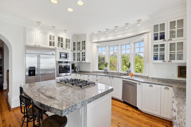 kitchen with built in appliances, sink, a center island, light wood-type flooring, and white cabinetry