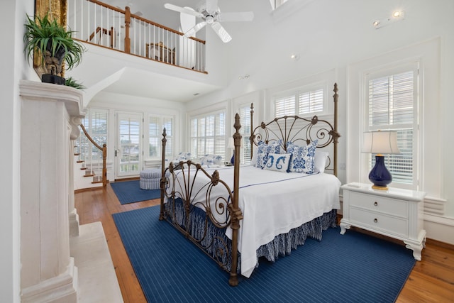 bedroom with a high ceiling, wood-type flooring, and ceiling fan