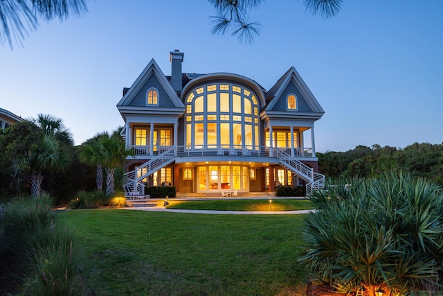 back house at dusk with a lawn