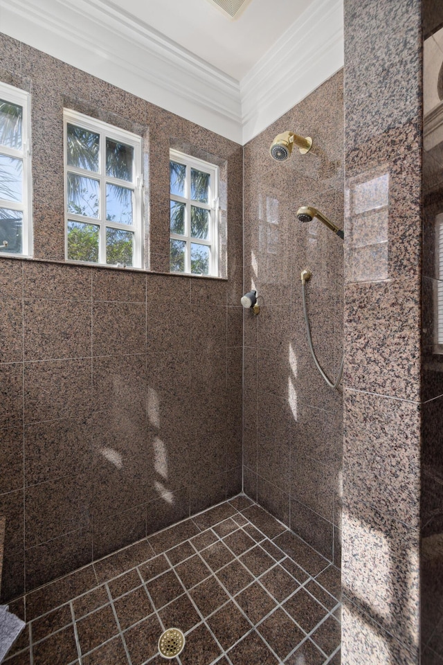 bathroom with ornamental molding and tiled shower