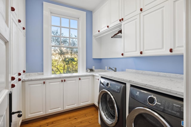 laundry area with independent washer and dryer, wood-type flooring, and cabinets