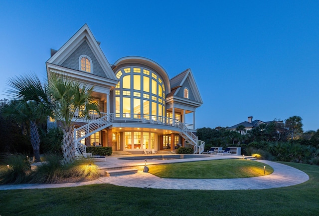 back house at dusk featuring a patio area and a yard