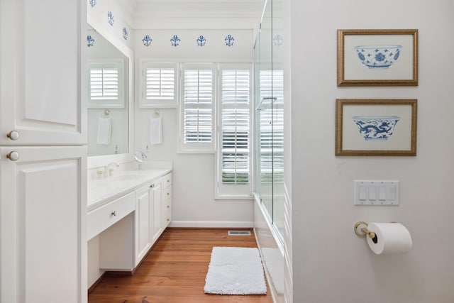 bathroom with vanity, hardwood / wood-style floors, and enclosed tub / shower combo