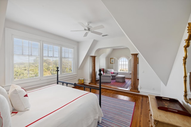 bedroom with ornate columns, ceiling fan, wood-type flooring, and multiple windows