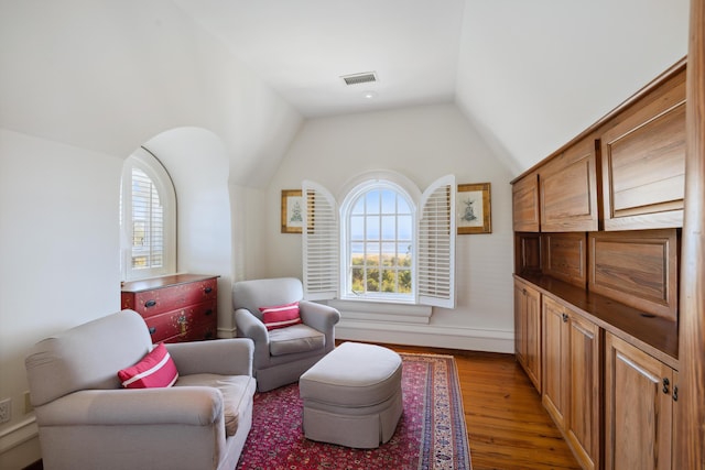 living area featuring lofted ceiling, light hardwood / wood-style flooring, and plenty of natural light