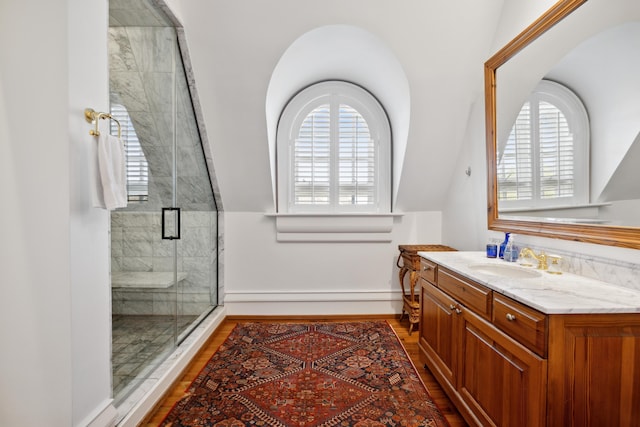 bathroom featuring vanity, lofted ceiling, wood-type flooring, and a shower with shower door