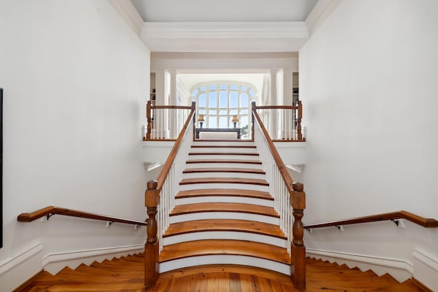 stairs featuring decorative columns, crown molding, and hardwood / wood-style flooring