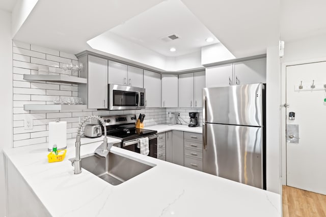 kitchen featuring gray cabinets, sink, kitchen peninsula, and stainless steel appliances