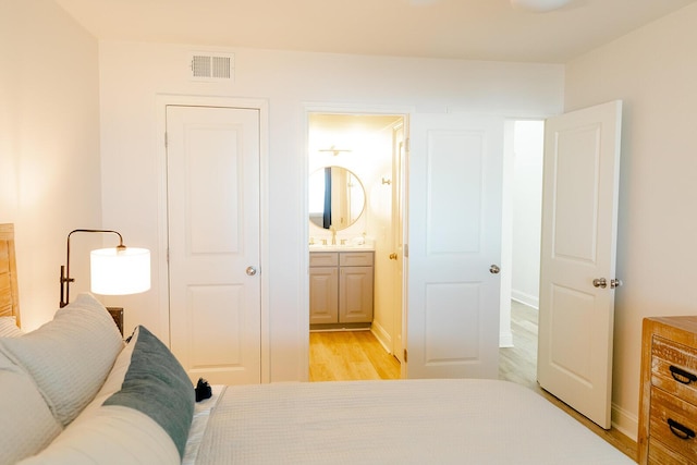 bedroom with ensuite bathroom and light wood-type flooring