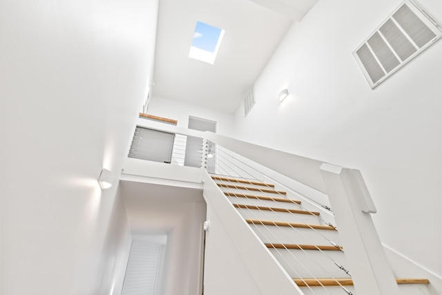 stairs with a towering ceiling and a skylight