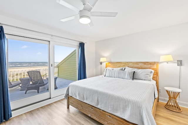 bedroom featuring access to exterior, ceiling fan, hardwood / wood-style floors, and a water view