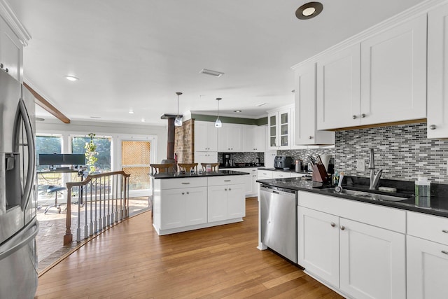 kitchen featuring white cabinets, decorative light fixtures, stainless steel appliances, and light wood-type flooring