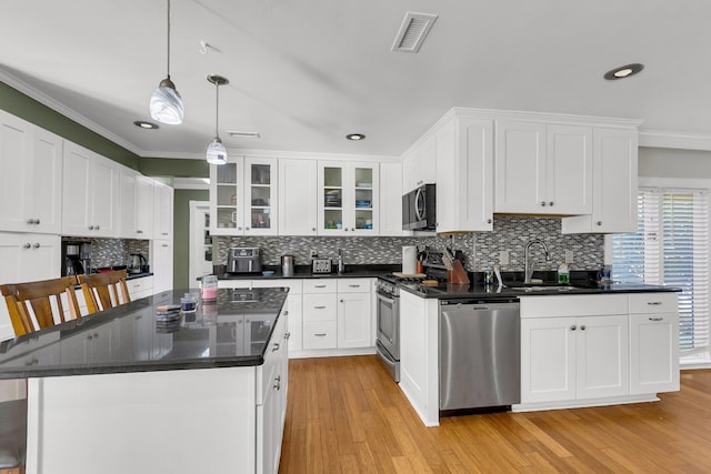 kitchen featuring a kitchen island, white cabinetry, a kitchen bar, sink, and stainless steel appliances