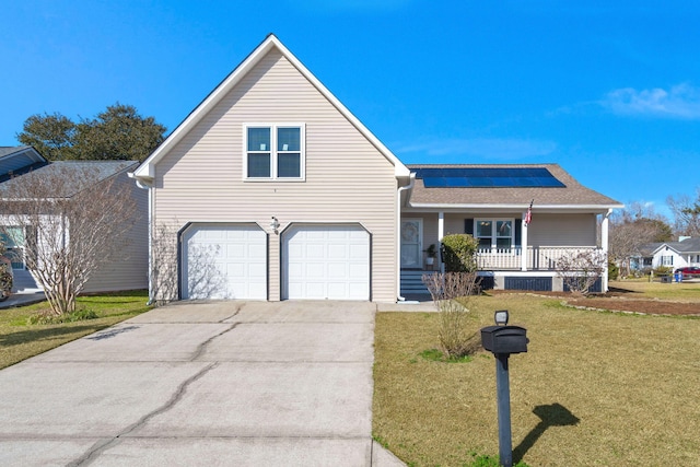 view of front of property featuring a porch, a garage, a front lawn, and solar panels