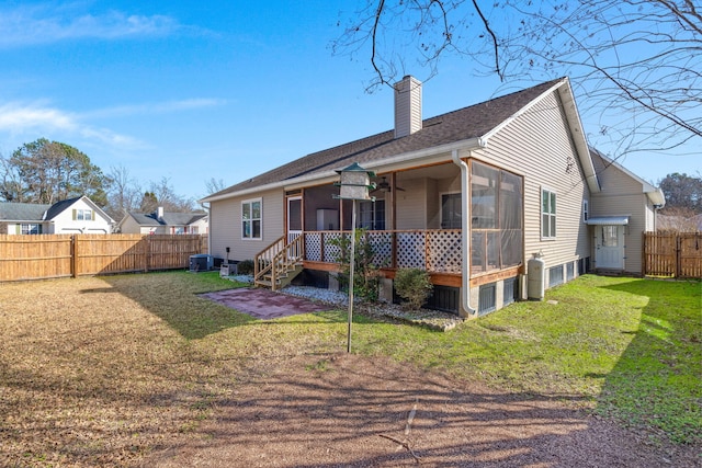 rear view of property featuring a sunroom and a lawn