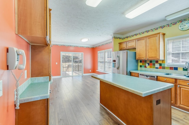 kitchen featuring appliances with stainless steel finishes, light countertops, light wood-style floors, and a sink