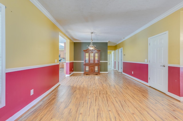 unfurnished room featuring ornamental molding, a textured ceiling, baseboards, and wood finished floors