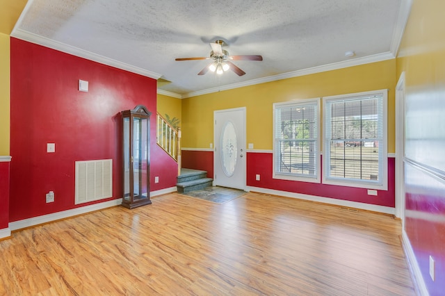 empty room featuring visible vents, stairs, ornamental molding, wood finished floors, and a textured ceiling