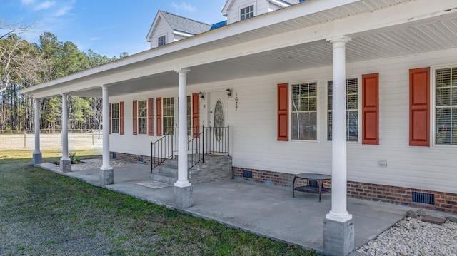 property entrance featuring a yard, covered porch, and crawl space