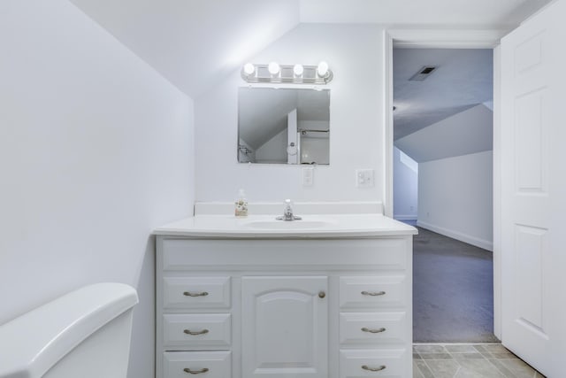 bathroom with visible vents, toilet, baseboards, vanity, and vaulted ceiling