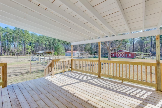 wooden terrace featuring a yard, a barn, an outdoor structure, and fence